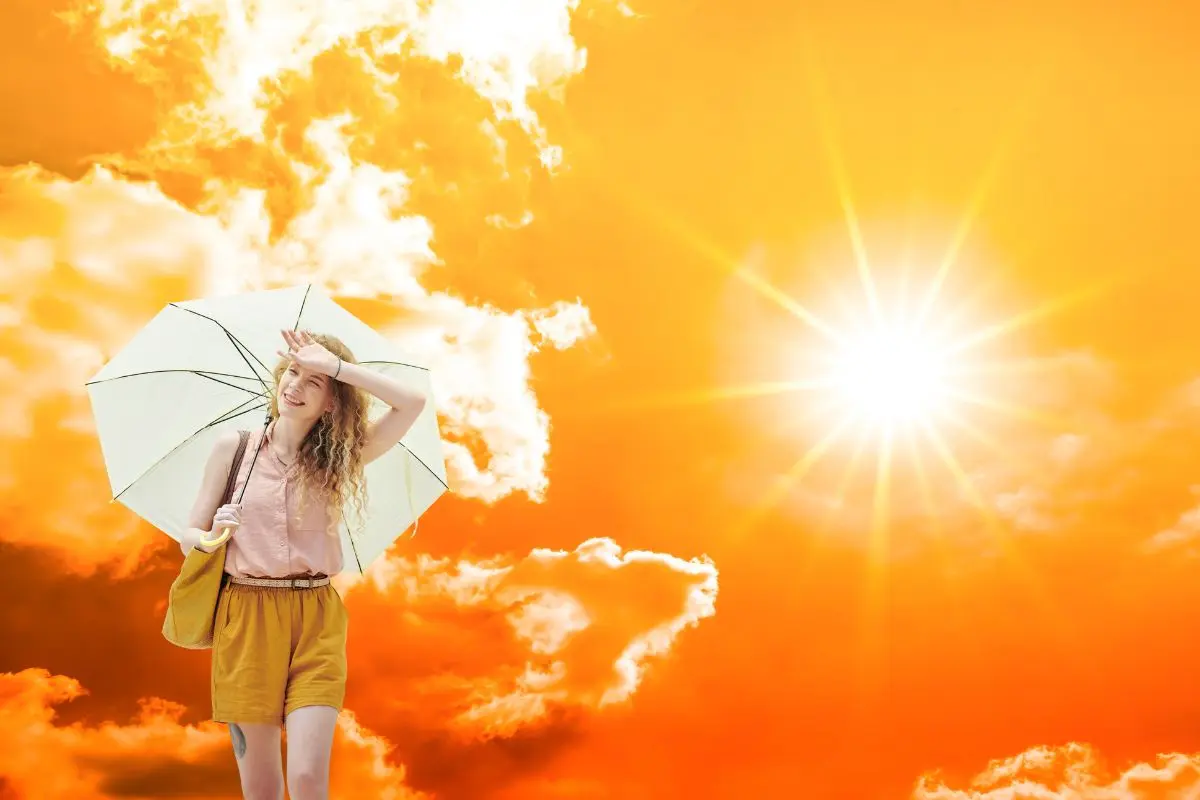 De fondo cielo soleado, mujer con paraguas acalorada Foto: Canva