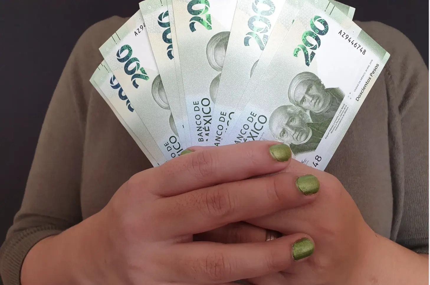 Mujer con billetes de 200 pesos. Foto: Canva