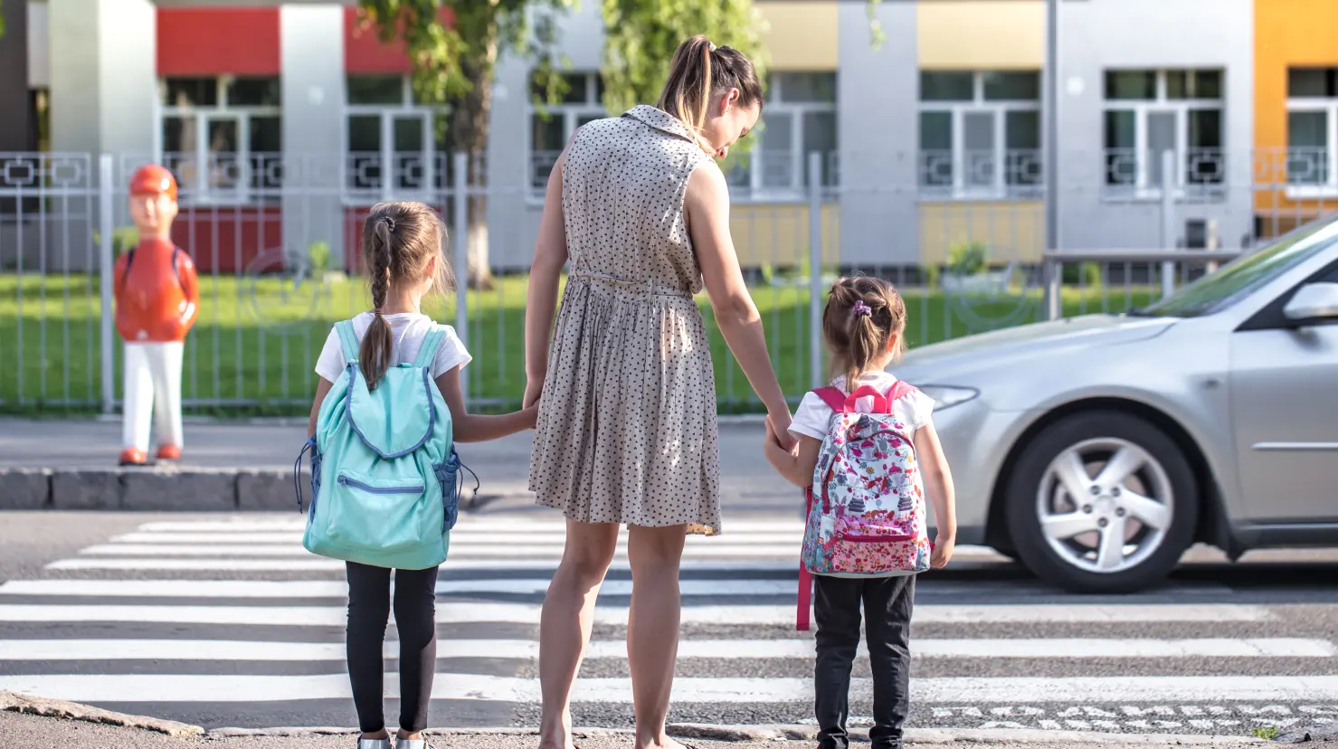 Mamá a punto de cruzar la calle junto con sus hijos en una zona escolar Foto: Freepik