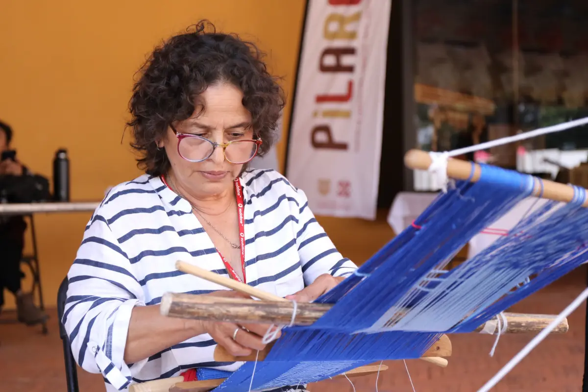 Mujer usando un telar de cintura en el taller de artesanías textiles de PILARES en CDMX. Foto: X (@CdmxPilares)