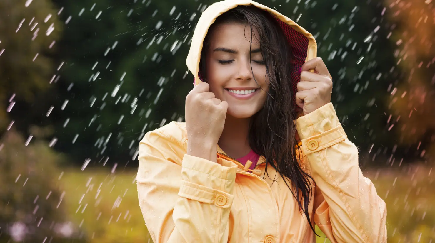 Mujer con impermeable cubriéndose de la lluvia. Foto: Freepik