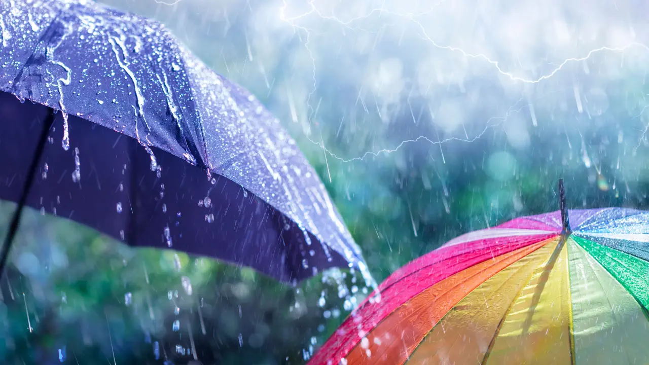 Dos personas caminan bajo la lluvia con paraguas en mano, una imagen cada vez más común en el Estado de México ante las constantes precipitaciones. Foto: Canva