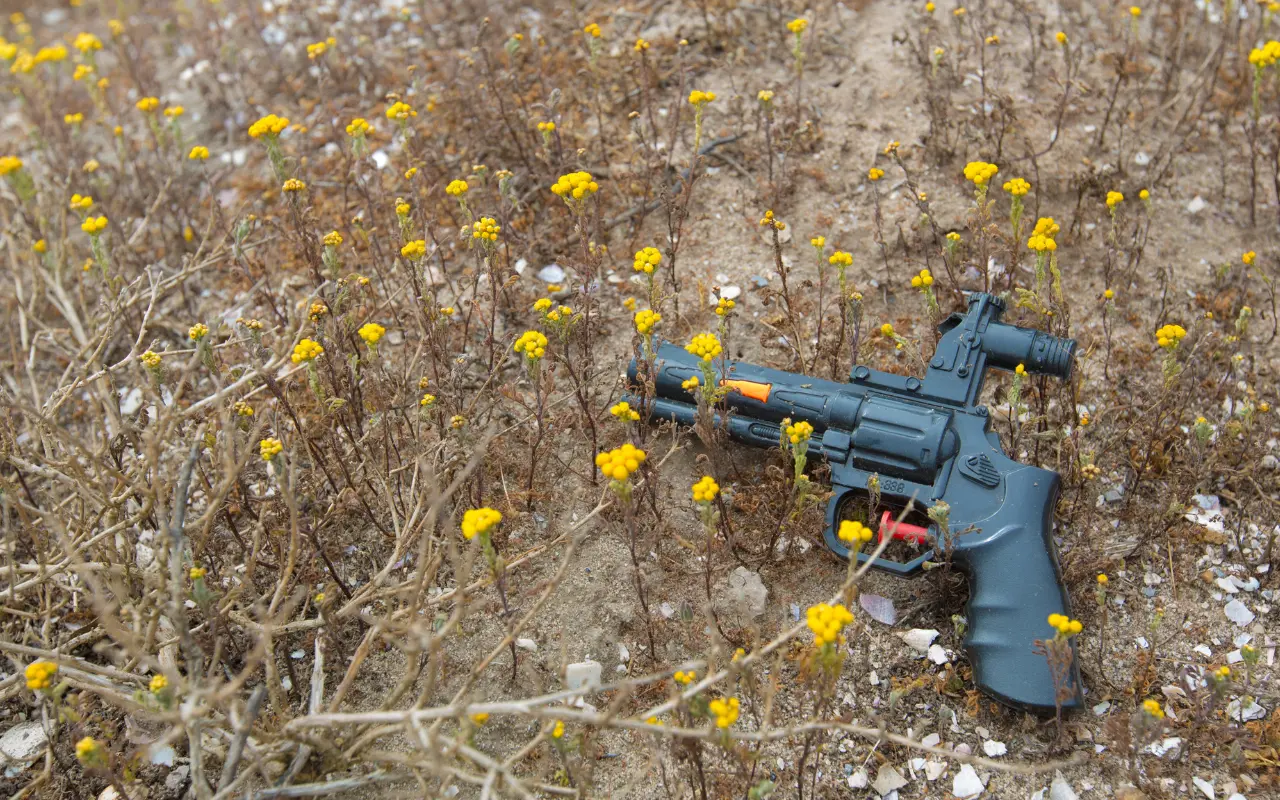 Pistola de juguete en el pasto. Foto: Canva