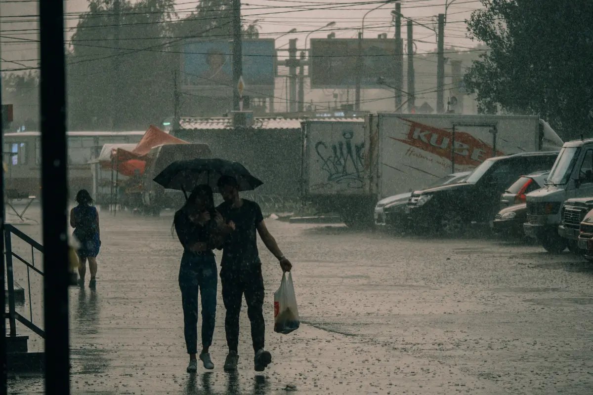 Pareja tapándose con paraguas en lluvia intensa en la CDMX. Foto: Canva