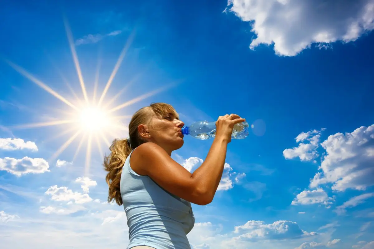 Día soleado con una mujer tomando agua Foto: Canva