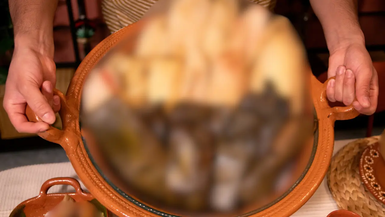 Alguien carga con cuidado una cazuela llena de tamales recién hechos. Foto: Canva