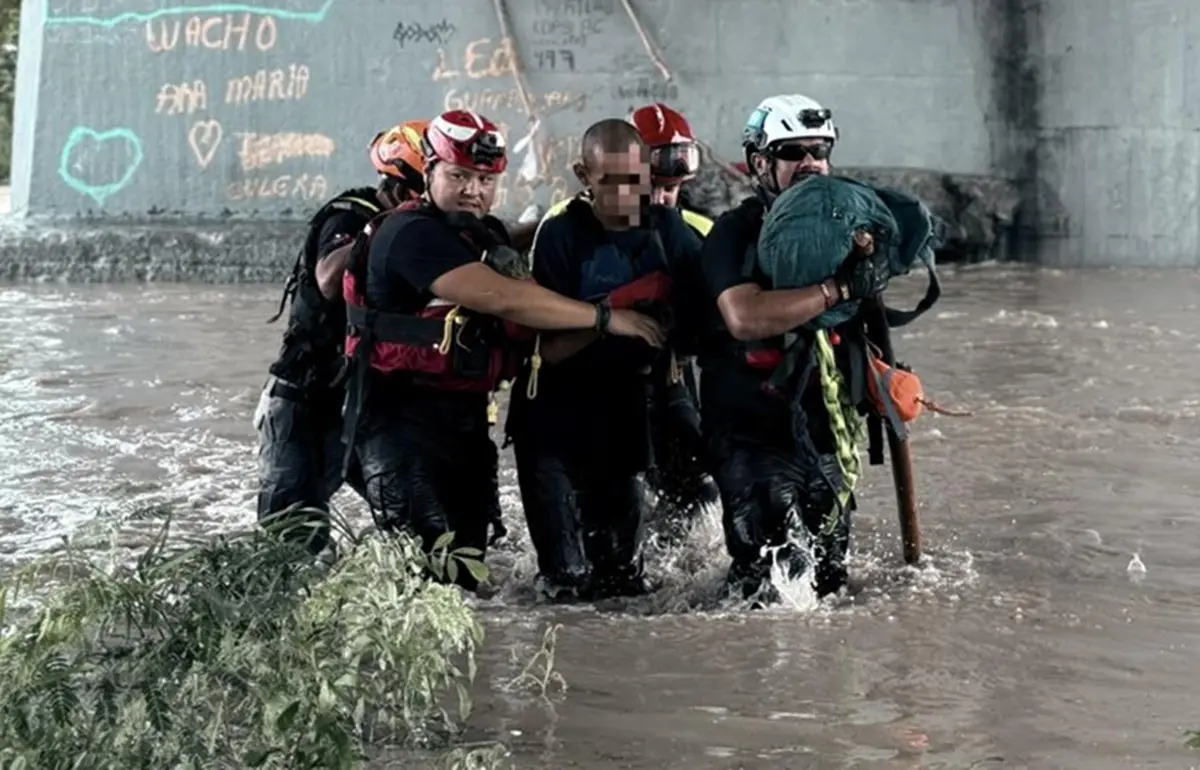 Elementos de Protección Civil rescatan a dos hombres tras quedar atrapados en la corriente del río Santa Catarina, a la altura del puente de la avenida Félix U. Gómez, en Monterrey.
