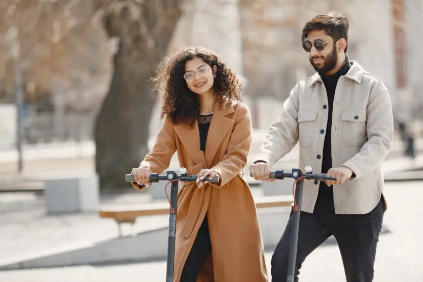 Pareja con scooters en la calle. Foto: Canva