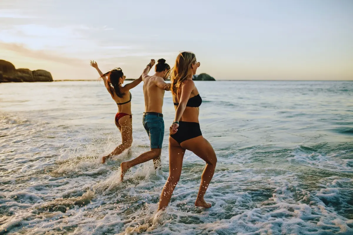 Tres jóvenes en la playa. Foto: Canva