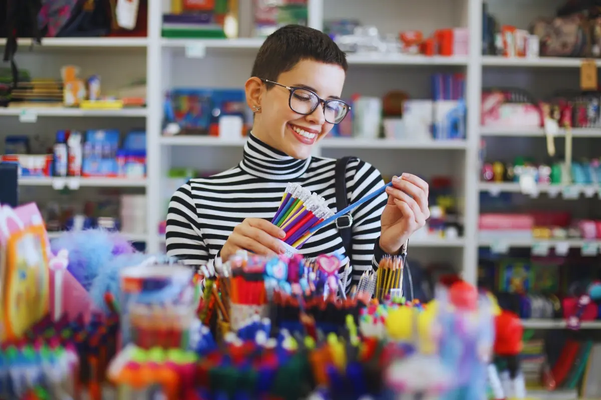 Joven comprando lápices en papelería. Foto: Canva