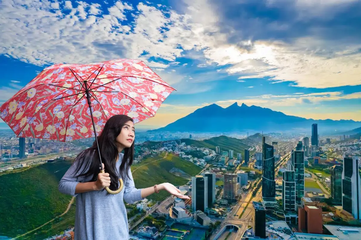 Mujer viendo si lloverá con paraguas en mano Foto: Canva