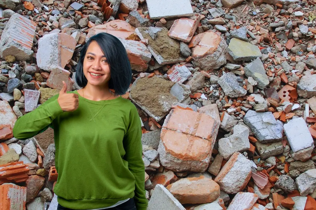 Mujer levantando el pulgar y de fondo escombro Foto: Canva