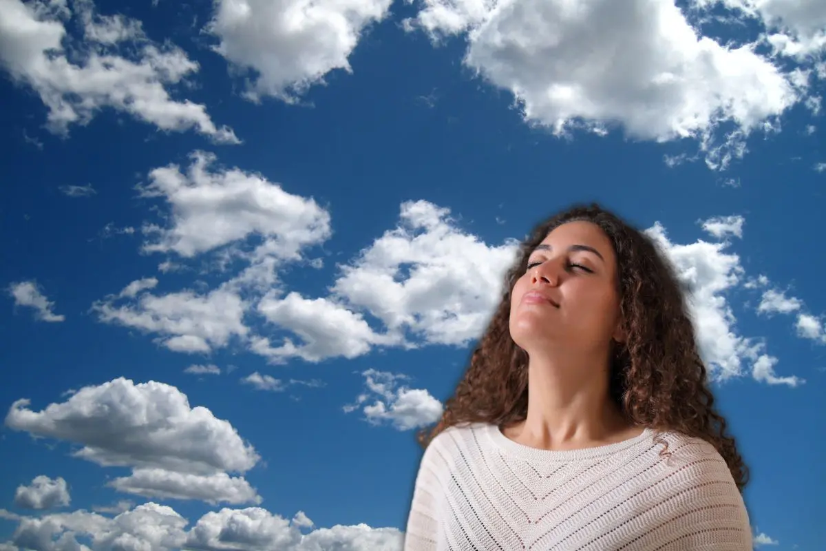 Mujer respirando y de fondo las nubes Foto: Canva