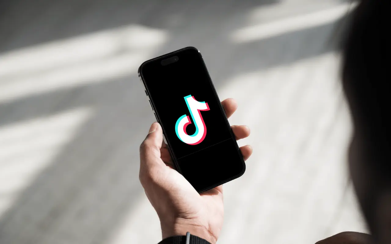 Persona sosteniendo celular con TikTok. Foto: Canva