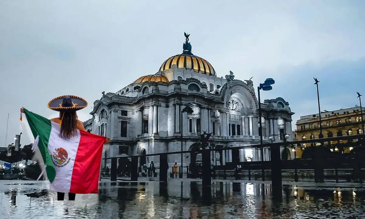 Bellas Artes después de lluvia, mujer con bandera de México. Foto: Pexels | Canva