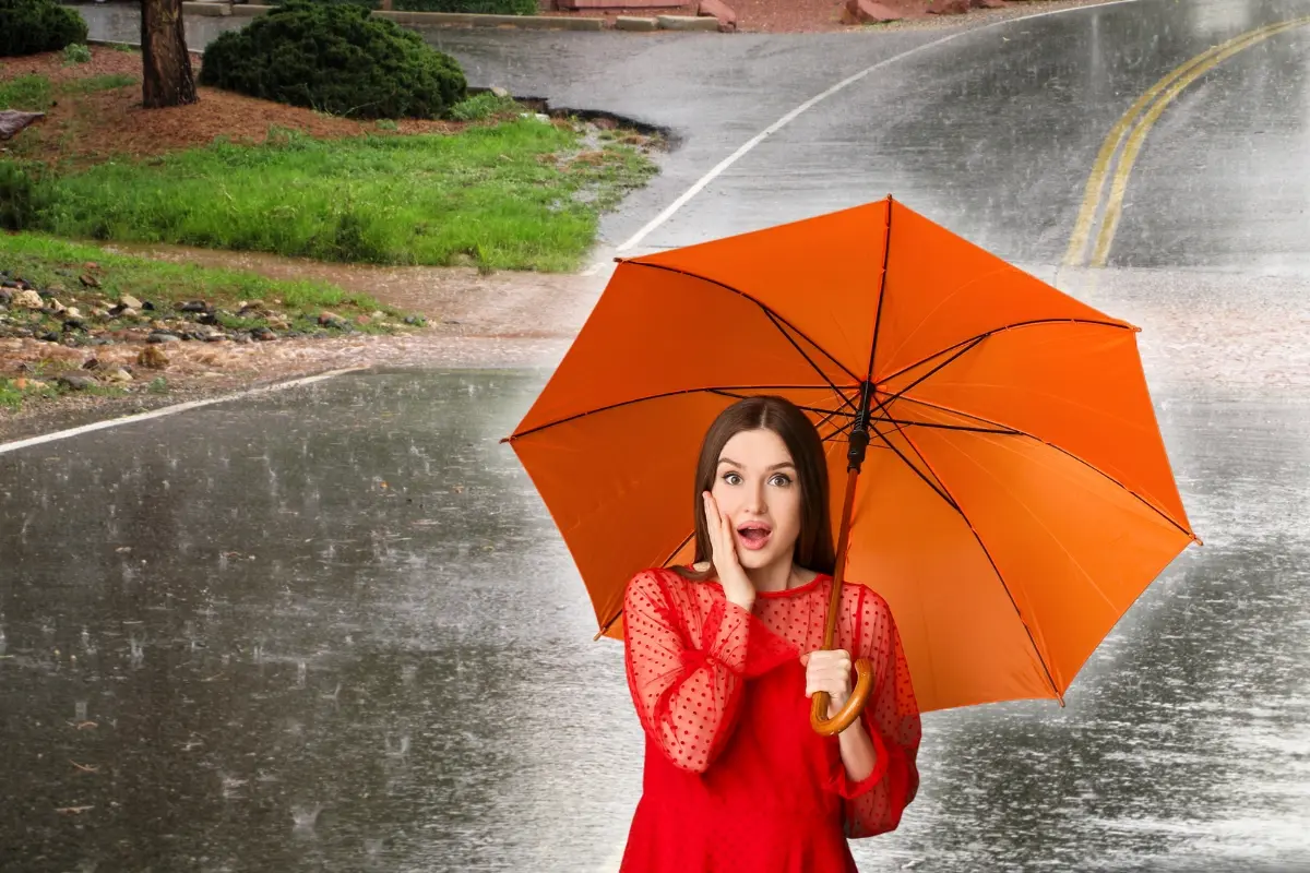 Una mujer con paraguas y lluvia en el fondo. Foto: Canva