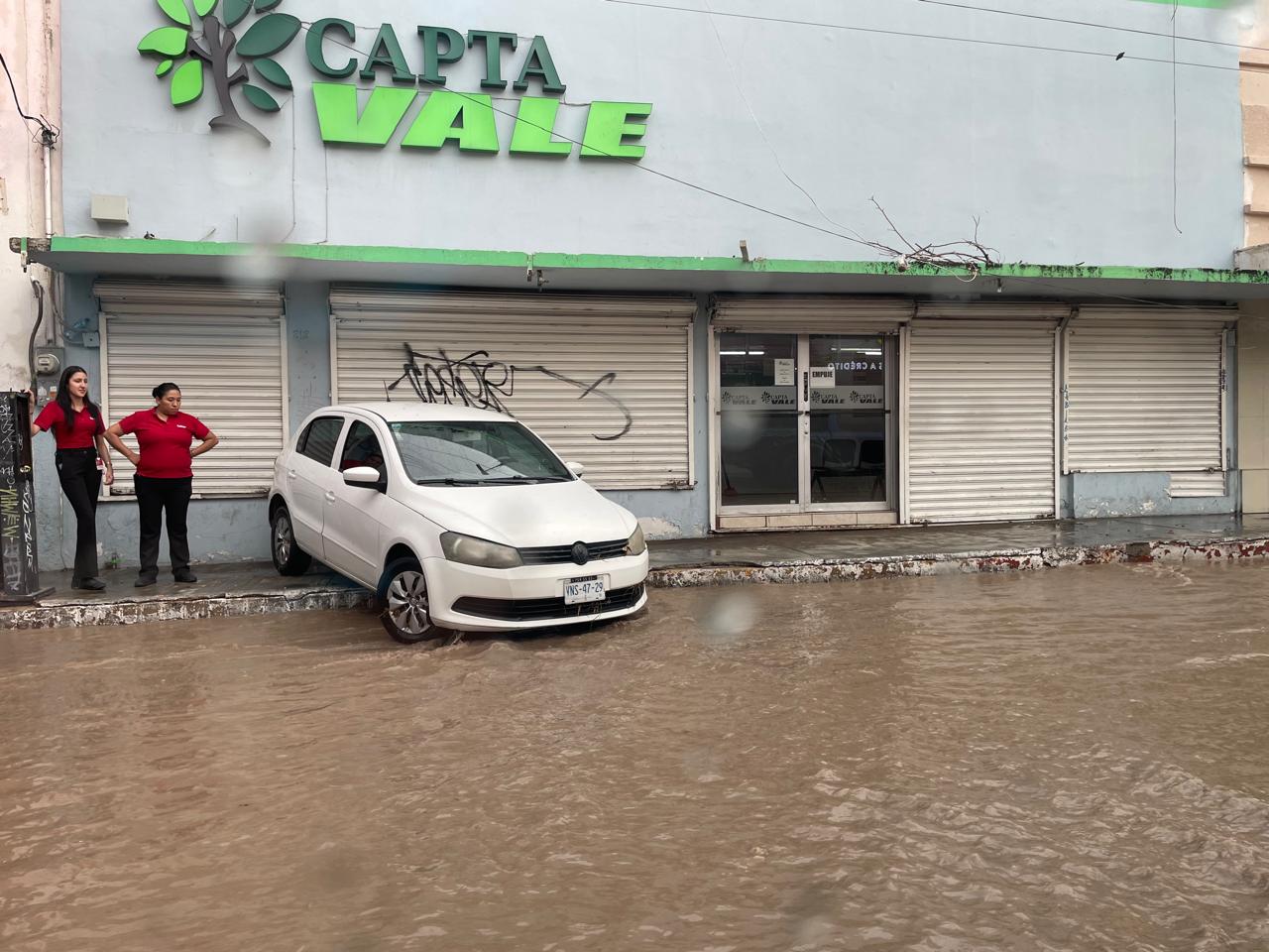 Vehículo es arrastrado por la corriente y queda varado en la banqueta Vehículo es arrastrado por la corriente y queda varado en la banqueta