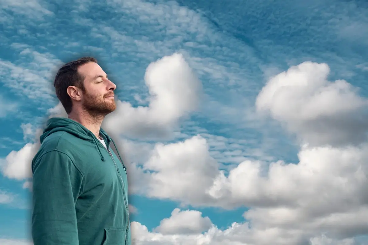 Hombre respirando profundamente y de fondo un cielo Foto: Canva