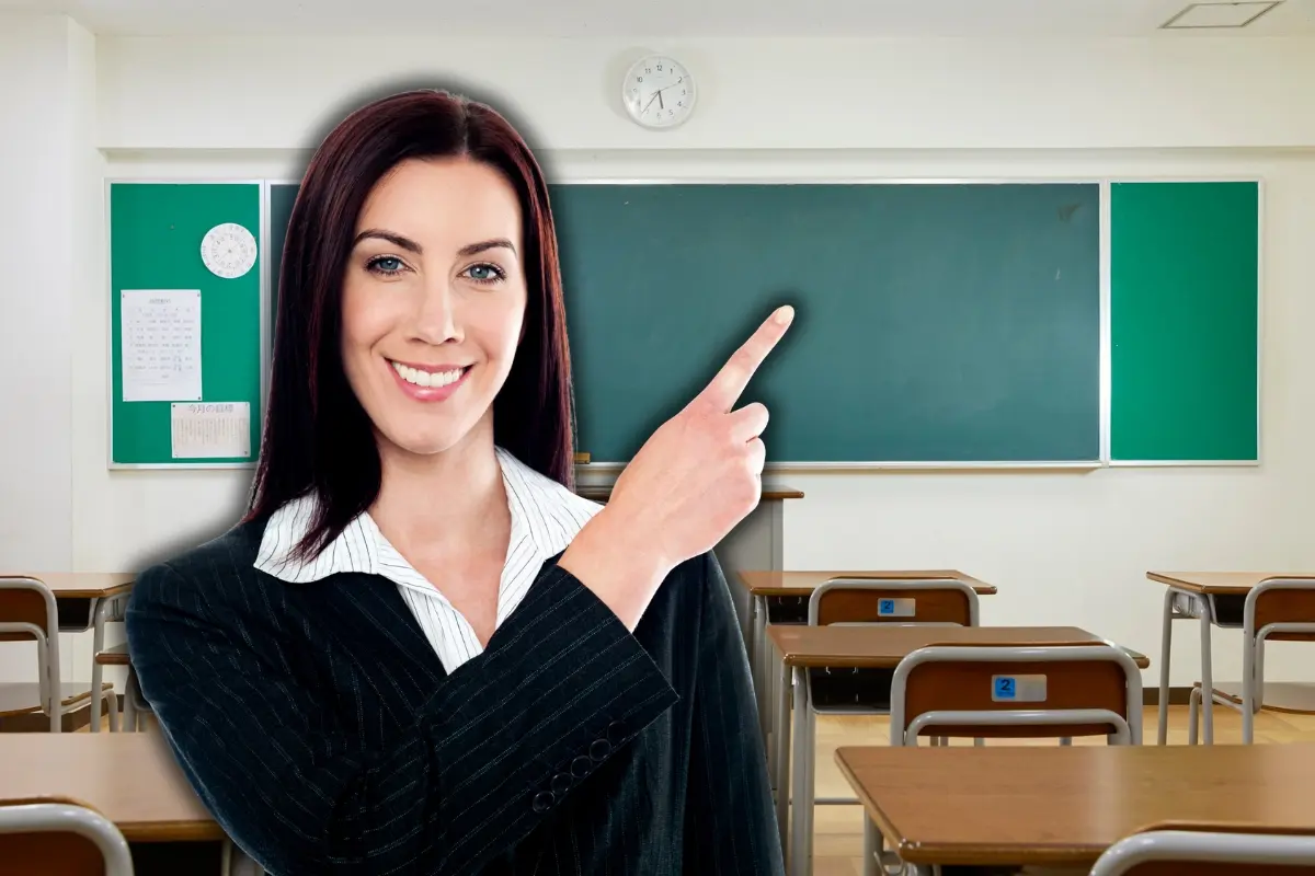 Una mujer señalando un pizarrón en un salón de clases. Foto: Canva