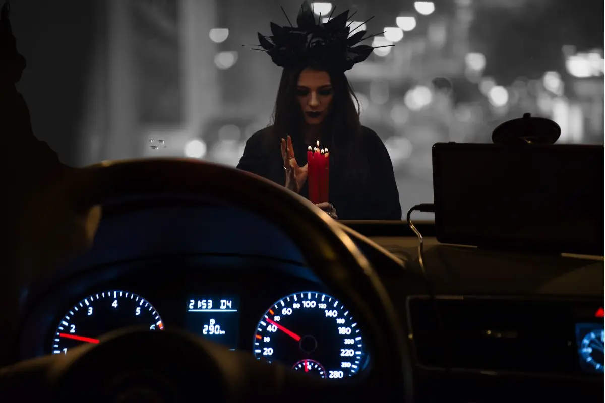 Automóvil por dentro y una mujer con capucha negra y vela en las manos Foto: Canva