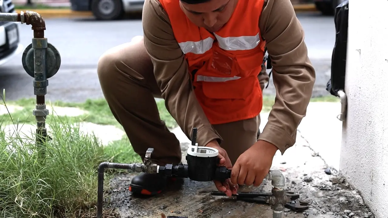 Un medidor de agua y una trabajador de Servicios de Agua y Drenaje de Monterrey. Foto: Servicios de Agua y Drenaje de Monterrey