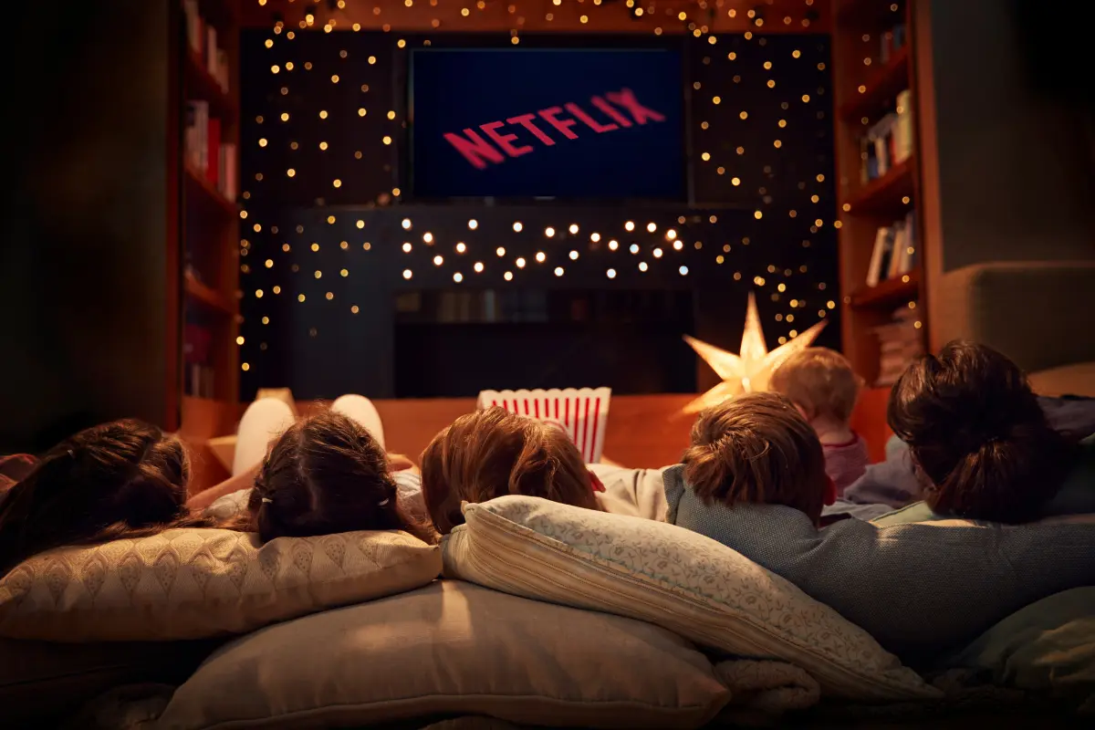 Familia acostada viendo Netflix en una pantalla (Foto: Canva)