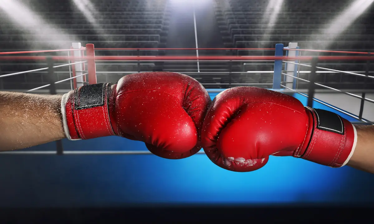 De fondo un ring y dos guantes de boxeo haciendo contacto. Foto: Canva/Alexis Lara