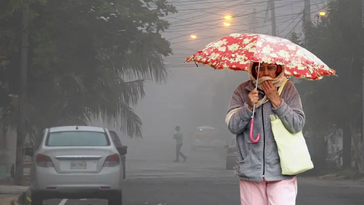 Calle con niebla y una mujer abrigada con un paraguas. Foto: Archivo POSTA Yucatán