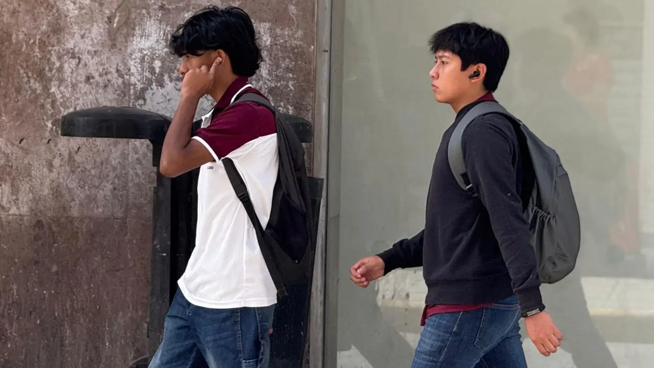 Dos personas caminan por las calles de Mérida usando suéter ante las bajas temperaturas que se han registrado en días recientes.- Fuente Irving Gil