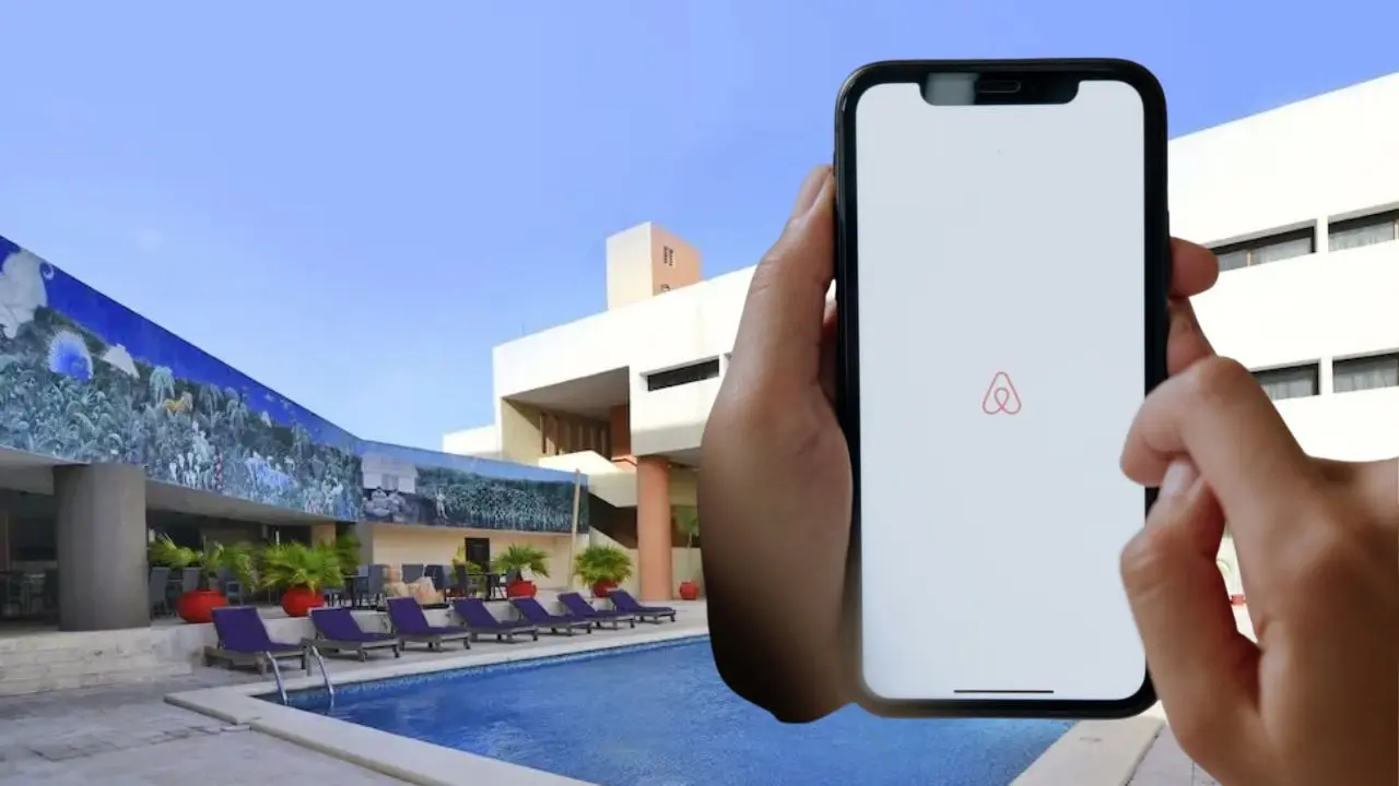 Al fondo, aspecto de uno de los hoteles ubicados en la ciudad de Mérida. Al frente, un celular con la aplicación abierta de Airbnb.- Fuente Christian Espadas