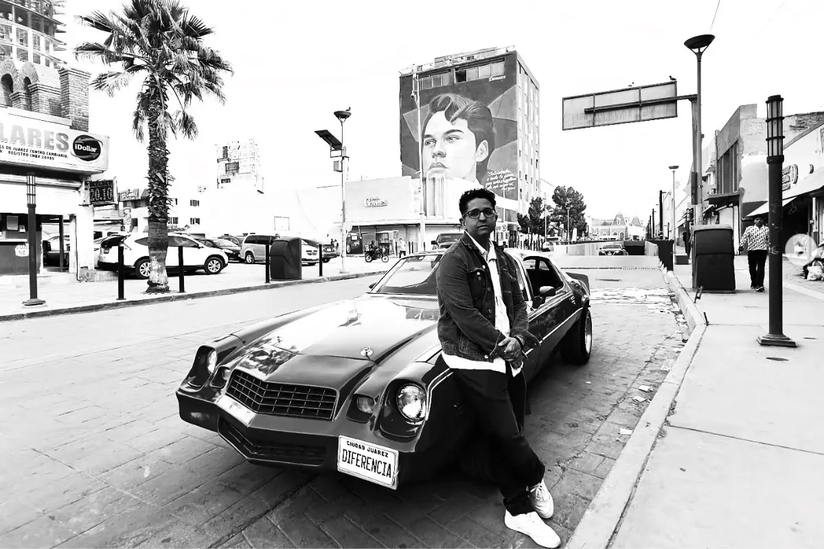 Jean Aguilera recargado en un carro y, de fondo, el mural de Juan Gabriel (Foto: IG @jeangabrielaguilera / Canva)