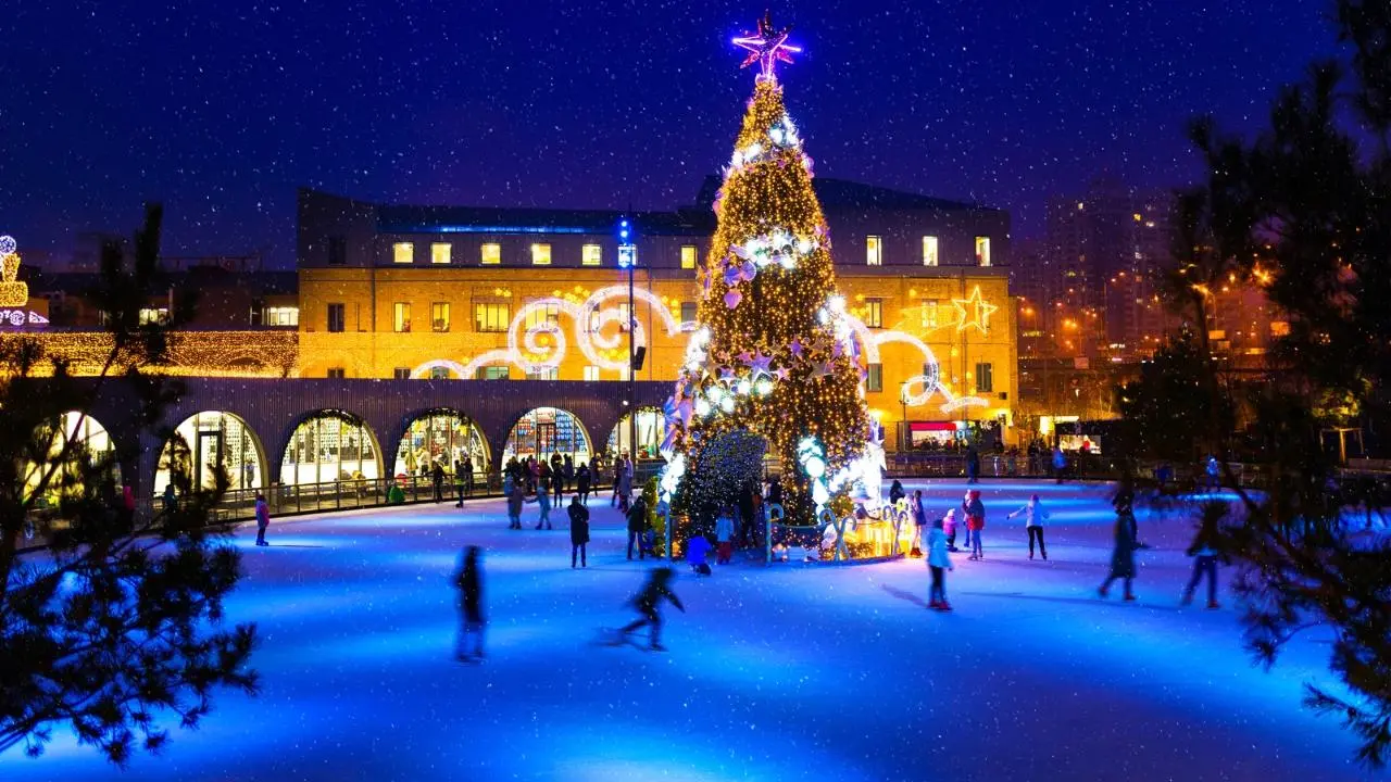 Pista de hielo iluminada con un gran árbol de Navidad. Foto: Canva
