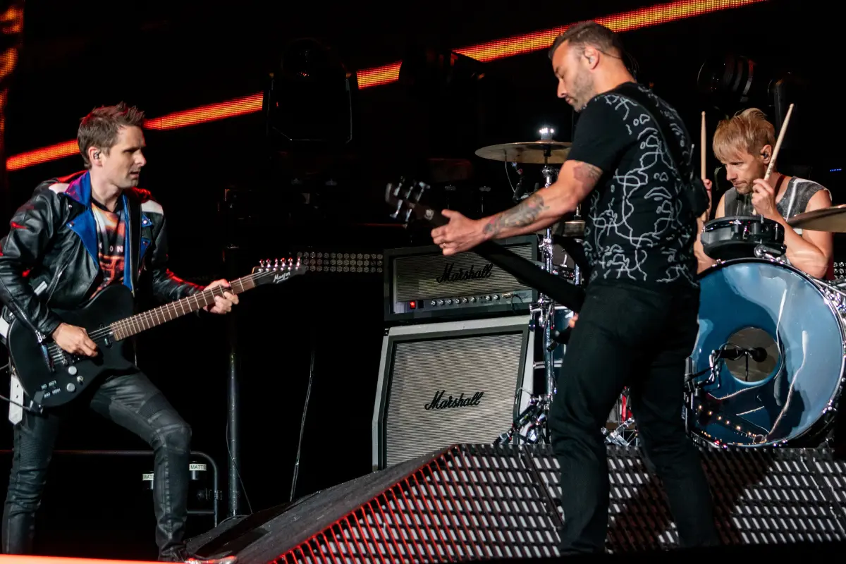 Matt Bellamy, Chris Wolstenholme y Dominic Howard, los tres integrantes de Muse, durante un concierto en vivo (Foto: IG @muse / Canva)