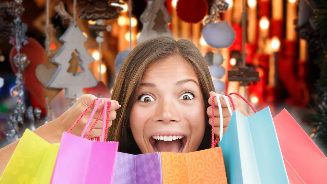 Una mujer con bolsas de compras y de fondo detalles navideños. Foto: Canva