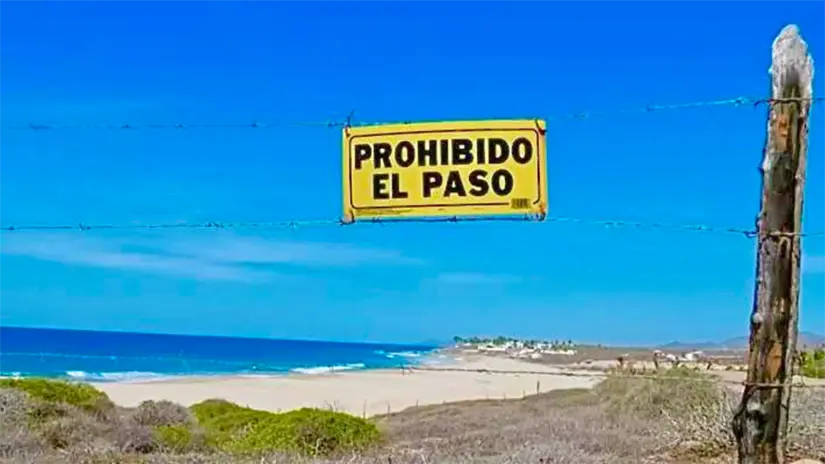 Un señalamiento de “Prohibido el paso” permanece colocado en el acceso a playa San Cristóbal, donde colectivos denuncian el cierre del camino público. Foto: Vive La Paz Mx / Facebook