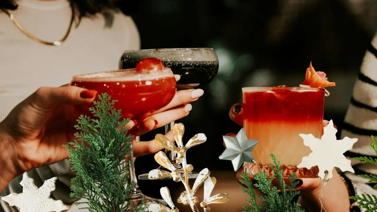 Personas disfrutan de bebidas con alcohol durante una reunión navideña.- Fuente Canva