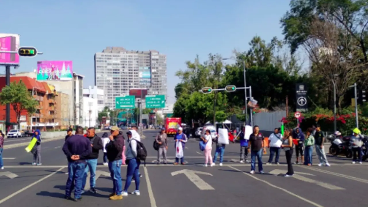 Grupo de personas realizando bloqueo vial durante marcha en CDMX