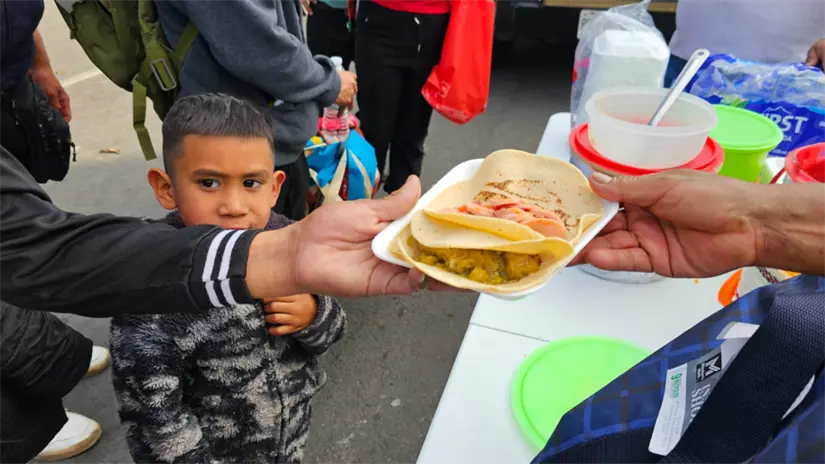 Familia recibiendo comida, en camino a la Basílica de Guadalupe. | Foto:  Luis Antonio Alfaro
