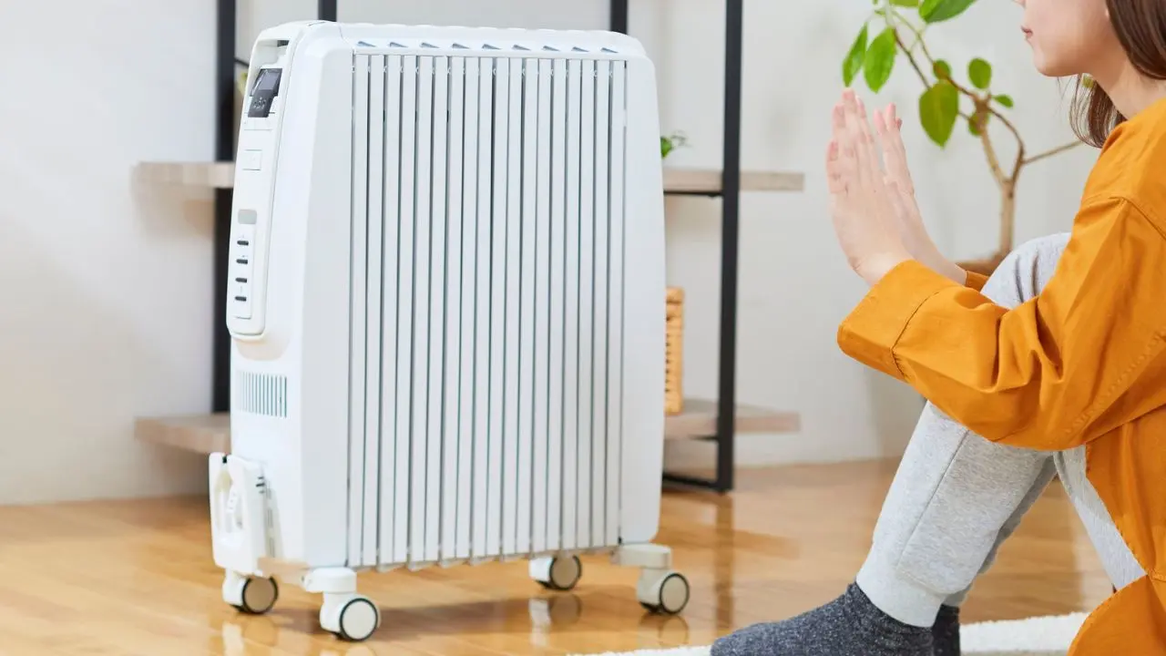 Persona colocando las manos frente a un calentador en un área bien ventilada del hogar. Foto: Canva