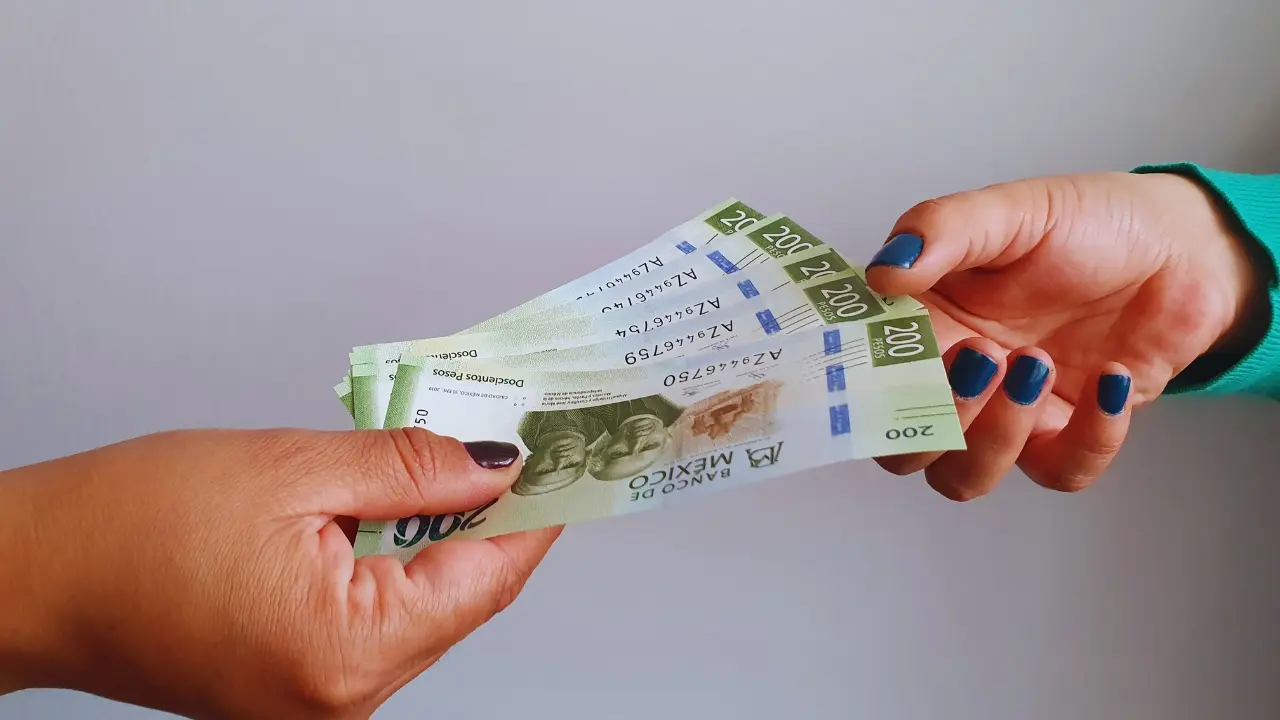 Dos manos de personas con dinero. Foto: Canva