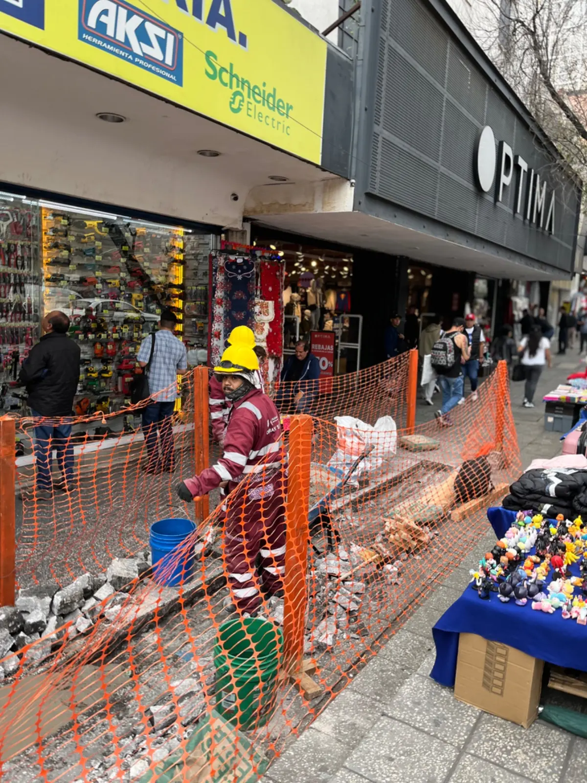 Un trabajador de la construcción, con casco amarillo y uniforme burdeos, realiza labores de mantenimiento en la acera. Foto: Iván Macías